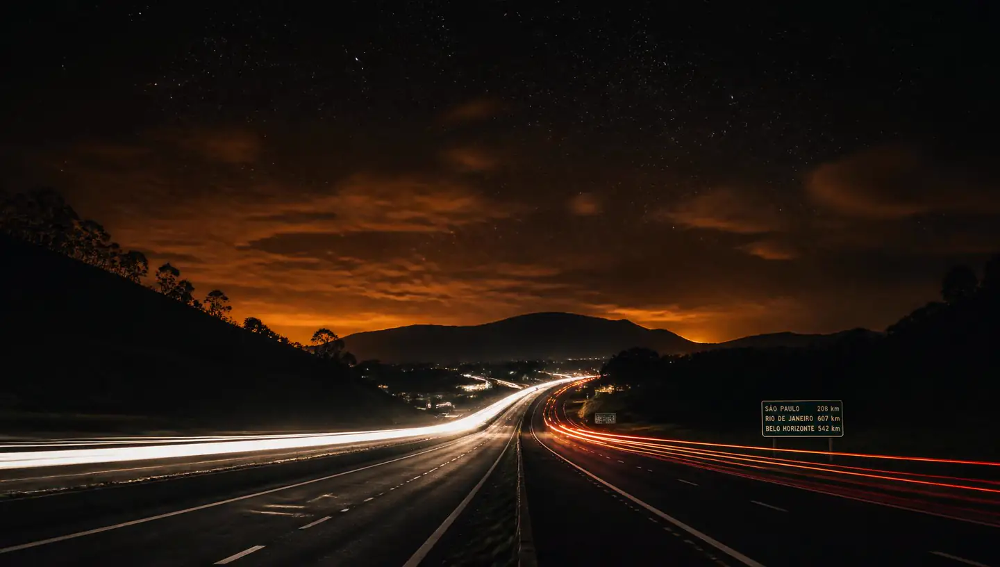 Estrada à noite com luzes de carro e céu estrelado
